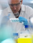 Biotecnologia Pesquisa, cientista vendo amostras em uma placa de vários poços durante um experimento no laboratório — Fotografia de Stock