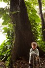 Young girl standing by tree — Stock Photo