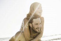 Man giving girlfriend piggyback in sea, Cape Town, South Africa — Stock Photo
