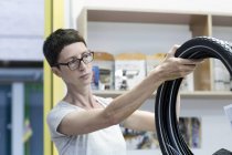 Frau in Werkstatt überprüft Fahrradreifen — Stockfoto