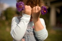 Young girl holding flowers in front of face — Stock Photo