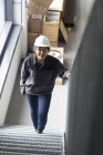 Женщина-работница, поднимающаяся по лестнице на заводе — стоковое фото