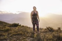 Plus size woman wearing sports clothing on mountain at sunrise — Stock Photo