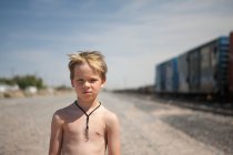 Хлопчик стоїть на залізничній колії і дивиться на камеру — стокове фото