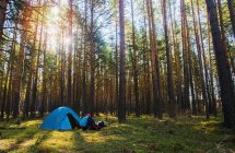 Femme par tente plantée dans la forêt — Photo de stock