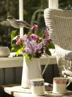 Arrangement de fleurs en cruche rustique sur la table d'appoint de la véranda — Photo de stock