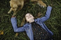 Jovem deitada na grama olhando para o seu Golden Retriever — Fotografia de Stock