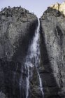 Towering rock face waterfall, Yosemite National Park, California, EE.UU. - foto de stock