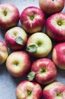 Вид сверху на красные свежие яблоки с листьями на столе — стоковое фото