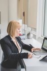 Reife Geschäftsfrau schaut auf Balkendiagramm auf Büro-Laptop — Stockfoto
