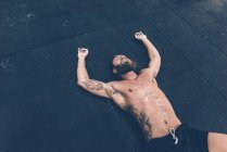 Erschöpfter männlicher Crosstrainer liegt auf dem Turnhallenboden — Stockfoto