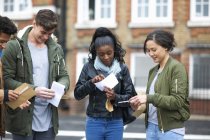 Estudiantes universitarios adultos jóvenes que leen los resultados del examen en el campus - foto de stock
