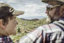 Sobre el hombro visión borrosa del hombre y el hijo adolescente mirándose en el paisaje, Bridger, Montana, EE.UU. - foto de stock