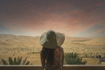 Mulher na varanda, olhando para a vista do deserto, ao pôr do sol, vista traseira, Abu Dhabi — Fotografia de Stock