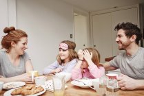 Parents adultes moyens à la table du petit déjeuner avec deux filles — Photo de stock