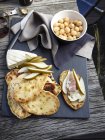 Vista superior de panes planos, taleggio, peras en rodajas, prosciutto y macadamias - foto de stock