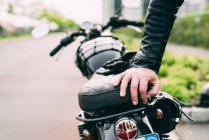 Рука чоловіка мотоцикліста, що спирається на мотоцикл — стокове фото