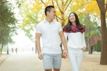Jovem casal passeando no outono árvore alinhada parque, Pequim, China — Fotografia de Stock