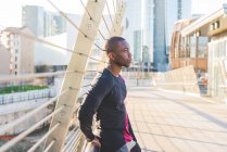 Young man standing on footbridge, pensive expression — Stock Photo
