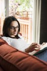 Frau liest Buch zu Hause auf Sofa — Stockfoto