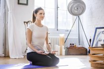 Mujer joven practicando meditación de yoga en apartamento - foto de stock