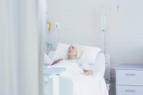 Doctor talking to worried senior female patient in hospital bed — Stock Photo