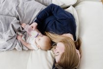 Visão aérea da mulher adulta média alimentando a filha do bebê no sofá — Fotografia de Stock