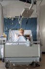 Paciente na revista de leitura de cama hospitalar — Fotografia de Stock