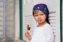 Portrait of female toddler leaning against shutters eating ice lolly, Beja, Portugal — Stock Photo