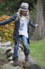 Mädchen tritt im Park über Baumstämme — Stockfoto