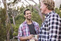 Two male hikers chatting over coffee in forest, Deer Park, Cape Town, South Africa — Stock Photo
