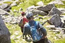 Cyclists carrying bicycles on rocky outcrop — Stock Photo