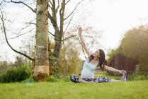 Pregnant woman exercising outdoors, stretching — Stock Photo