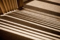 Janela persianas lançando sombra no tapete — Fotografia de Stock