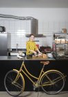 Retrato de camarera rebanando pan en la cafetería de reparación de bicicletas hipster - foto de stock