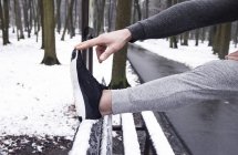 Mann streckt sich im verschneiten Park, abgeschossen — Stockfoto