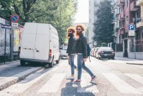 Молодые близнецы-хипстеры с рыжими волосами и бородами прогуливаются по пешеходному переходу — стоковое фото