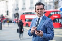 Businessmen in street with smartphone and earbuds, London, UK — Stock Photo