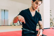 Artista marcial en gimnasio preparando espada - foto de stock