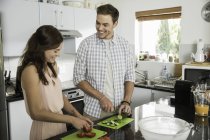 Счастливая пара режет овощи на кухне — стоковое фото