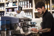 Giovane barista maschio utilizzando la macchina del caffè in caffè — Foto stock