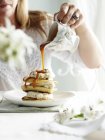 Frau gießt Toffee-Sauce aus verziertem Krug auf Stapel von Pikelets — Stockfoto