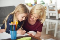 Бабуся допомагає онуці з домашнім завданням вдома — стокове фото