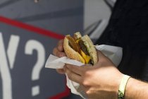 Male customer's hand eating hamburger from fast food van — Stock Photo