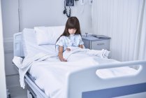 Menina paciente na cama olhando para baixo no braço gesso elenco na enfermaria infantil do hospital — Fotografia de Stock