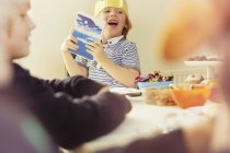 Little boy holding up opened Christmas present at table — Stock Photo