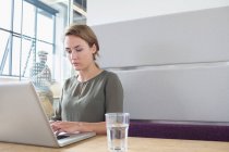 Молода жінка друкує на ноутбуці в офісі — стокове фото