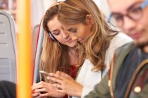 Two young female friends on train, looking at smartphone — Stock Photo