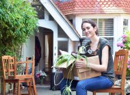 Junge Frau sitzt mit Pappschachtel vor neuem Haus — Stockfoto