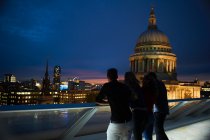 Silhouetted rear view of two young couples looking out to St Pauls at night, London, UK — Stock Photo